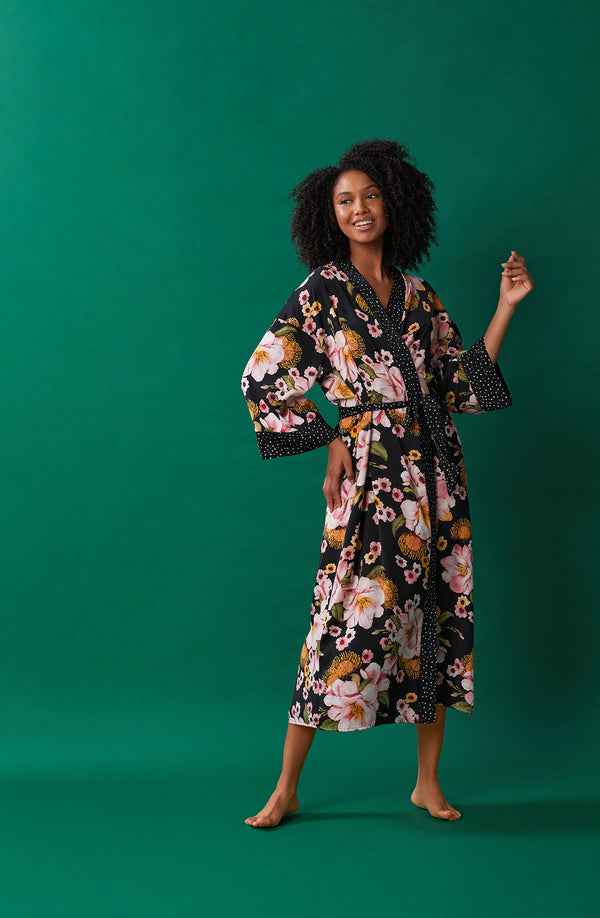 A lady wearing black long sleeve lydia maxi robe with midnight magnolia print.