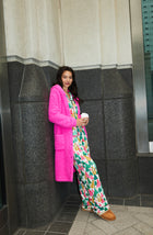 A Lady Wearing Maisie Sherpa Long Jacket In Holly Jolly Pink posing at a side angle while standing outdoors