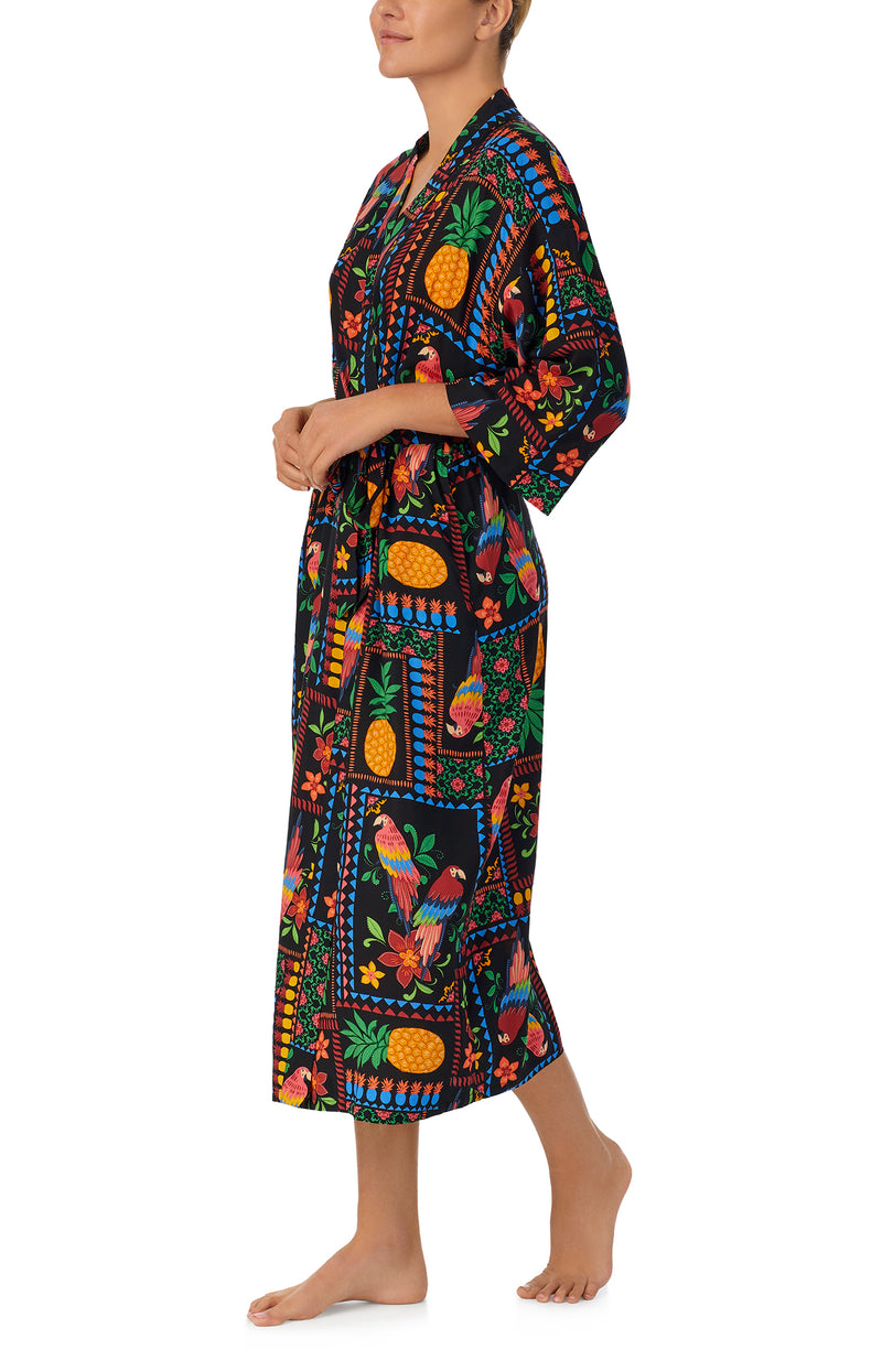 A lady wearing black short sleeve Lydia Maxi Robe with Tropical Fiesta print.