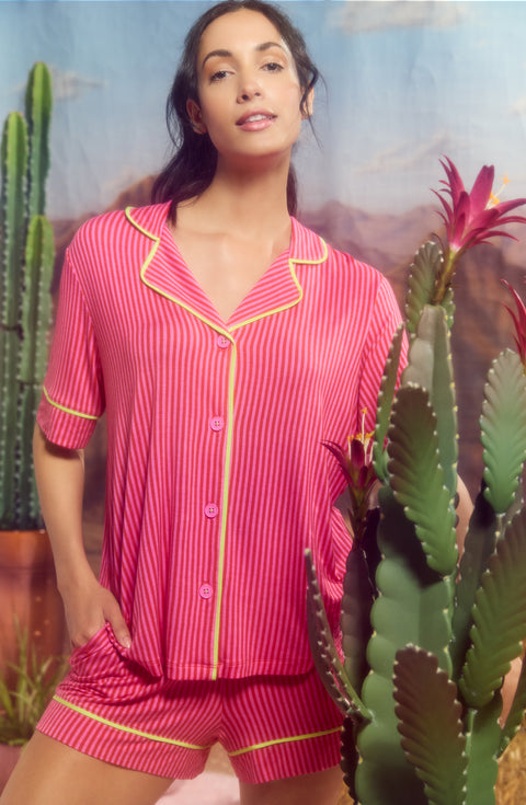 A Lady Wearing Dakota Short Knit Pj Set In Berry Stripe standing next to a plant