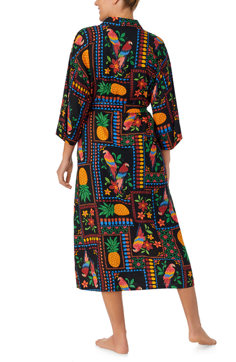 A lady wearing black short sleeve Lydia Maxi Robe with Tropical Fiesta print.