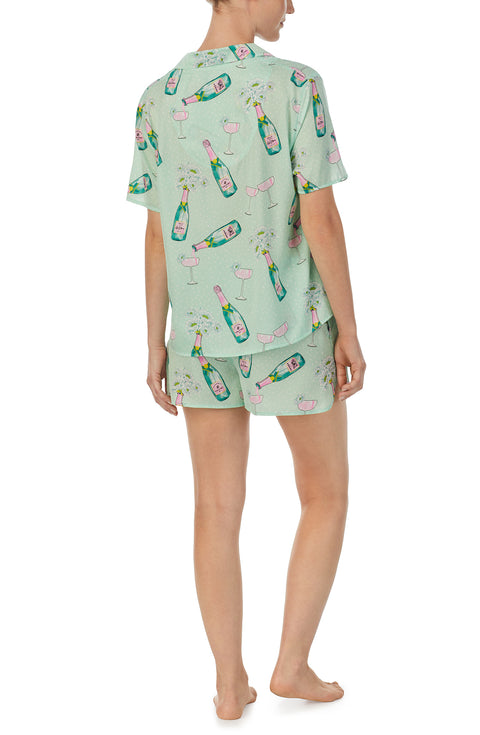 A lady wearing green short sleeve florence pj set in bubbly blossoms with champagne flowers print.