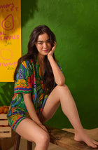 A Lady Wearing Georgia Short Woven Pj Set in Jungle Breeze in a Side Angle Sitting Pose