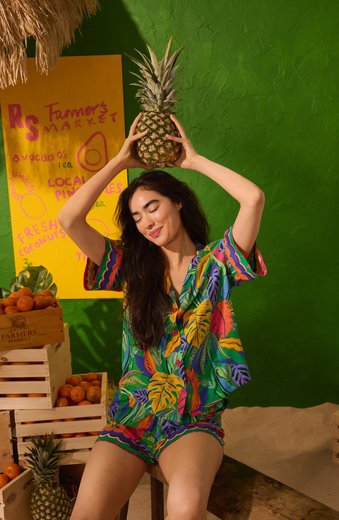 A Lady Wearing Georgia Short Woven Pj Set in Jungle Breeze Posing with Pineapple