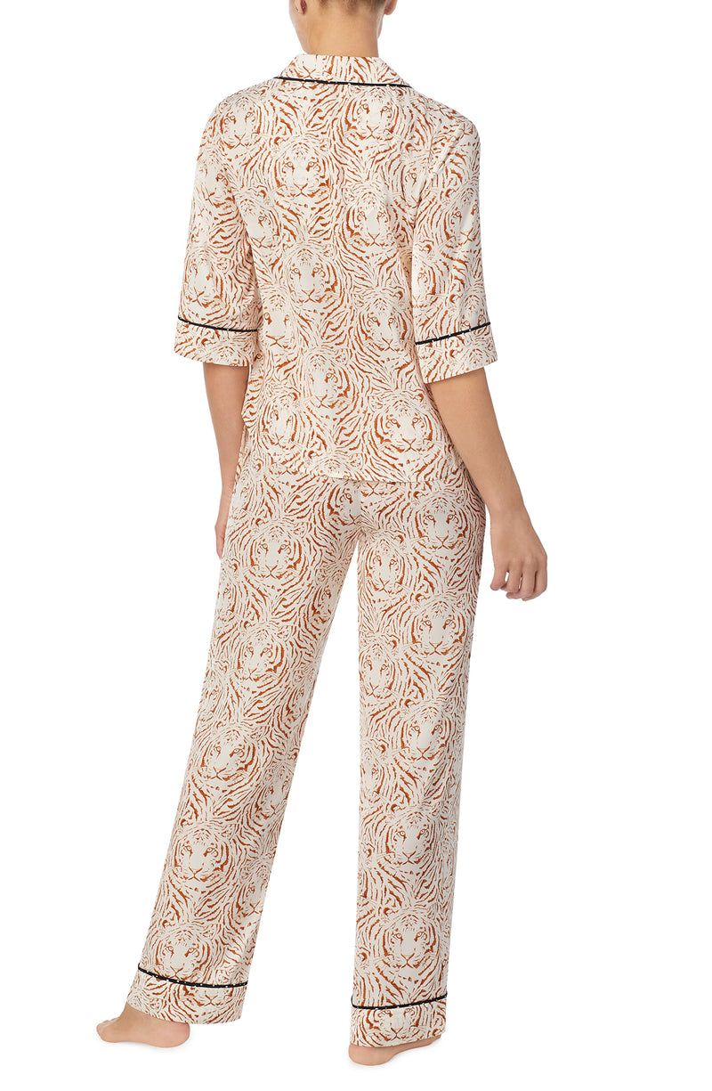 A lady wearing white quarter sleeve gramercy pj set with golden gaze print.