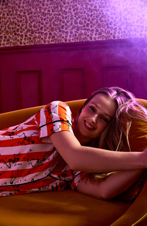 A Lady Wearing Sienna Long Knit Pj Set In Haunted Happy Hour laying on a sofa with a smile on her face