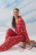 A Lady Wearing Collette Knit Pj Set In Country Claus sitting elegantly on a winter skating board in a snowy winter landscape while wearing stylish snow headphones