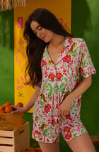 A Lady Wearing Dakota Short Knit Pj Set In Rainforest Escape shown in a front view pose holding an orange