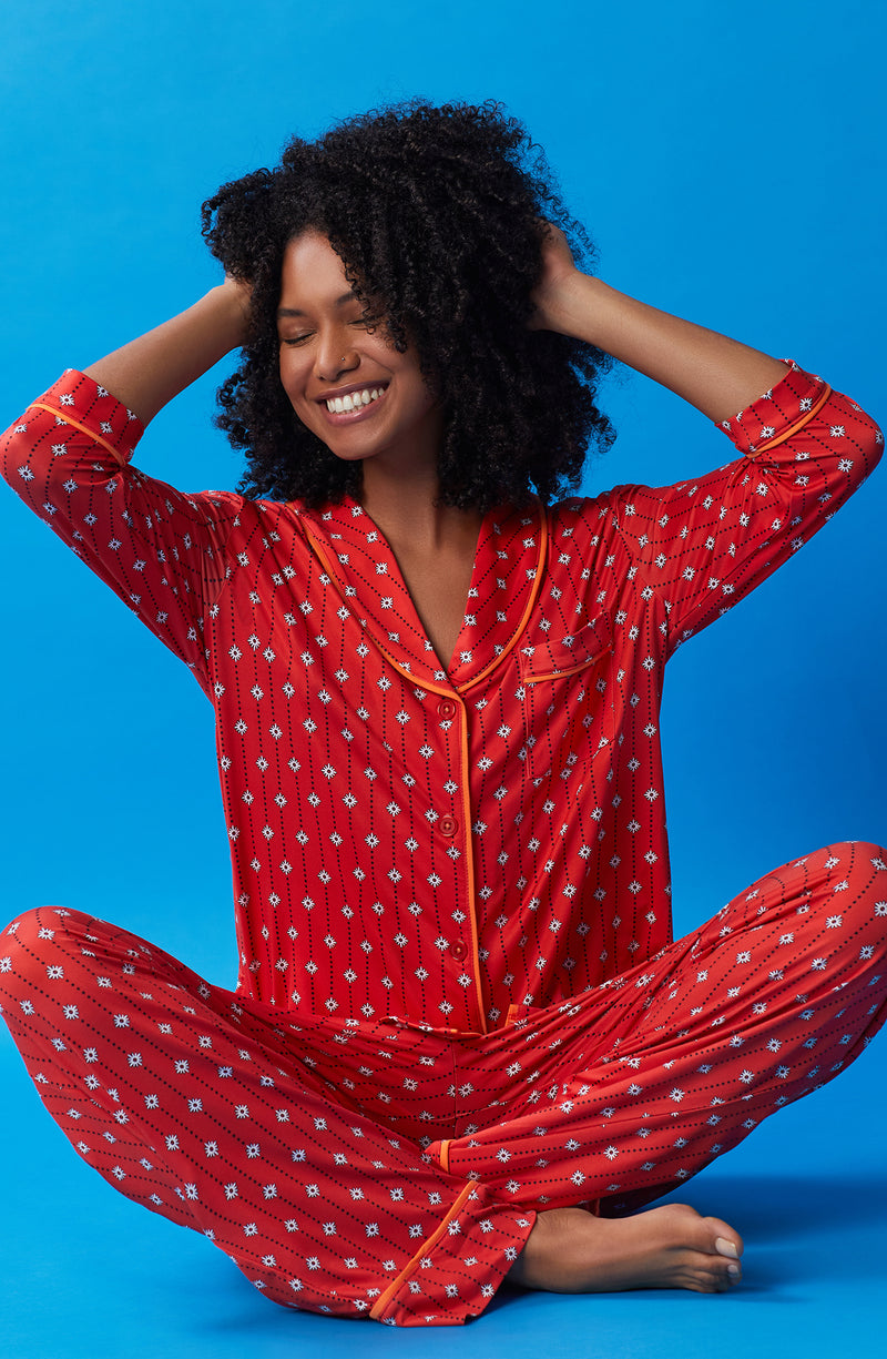 A lady wearing orange quarter sleeve reagent pj set with daisy dots print.