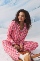A Lady Wearing Collette Knit Pj Set In Sugar Stripe while sitting on a winter skateboard