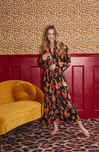 A Lady Wearing Madilyn Knit Robe In Flora & Fierce posing in a front facing view against a leopard print wall