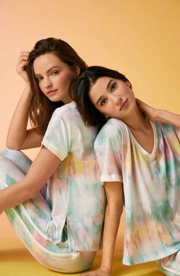 2 girls wearing short sleeve pajama sets with multi colour tie dye design.