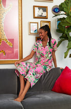 A lady wearing a pink crop pant with green floral pattern.