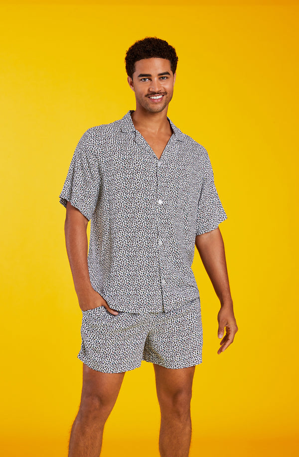 A man wearing a short sleeve boxer pj set with  black and white feline pattern.