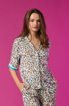 A lady wearing a multi colour short sleeve top with a tile pattern.