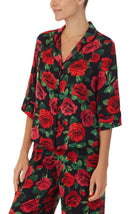 A lady wearing a black short sleeve top with red rose flowers pattern.