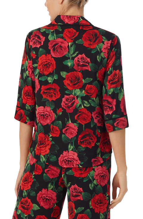 A lady wearing a black short sleeve top with red rose flowers pattern.