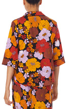 A lady wearing a black elbow sleeve gramercy top with multi color floral pattern.