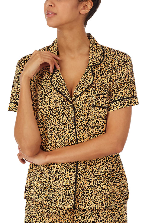 Upper part of a girl wearing short sleeve top with leopard skin design.