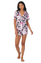 A lady wearing a short sleeve notch top and boxer pj set with pink watercolor floral pattern.