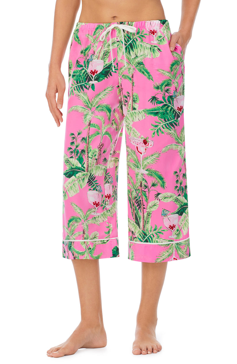 A lady wearing a pink crop pant with green floral pattern.
