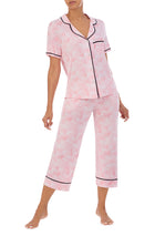 A girl wearing a short sleeve top and crop pant pajama set with pink balloon design.