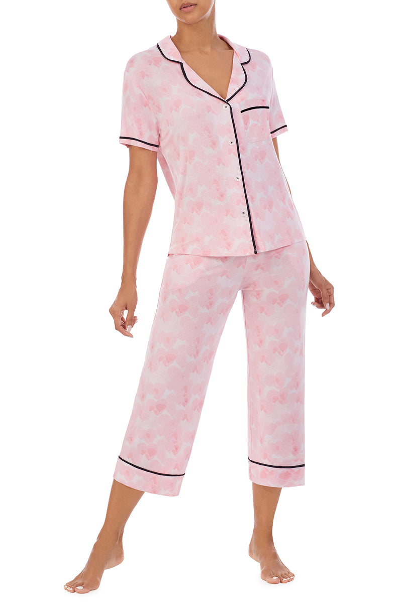 A girl wearing a short sleeve top and crop pant pajama set with pink balloon design.