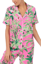 A lady wearing a pink short sleeve top with green floral pattern.