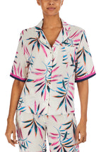 A lady wearing a white short sleeve top with multi colour palm leaves pattern