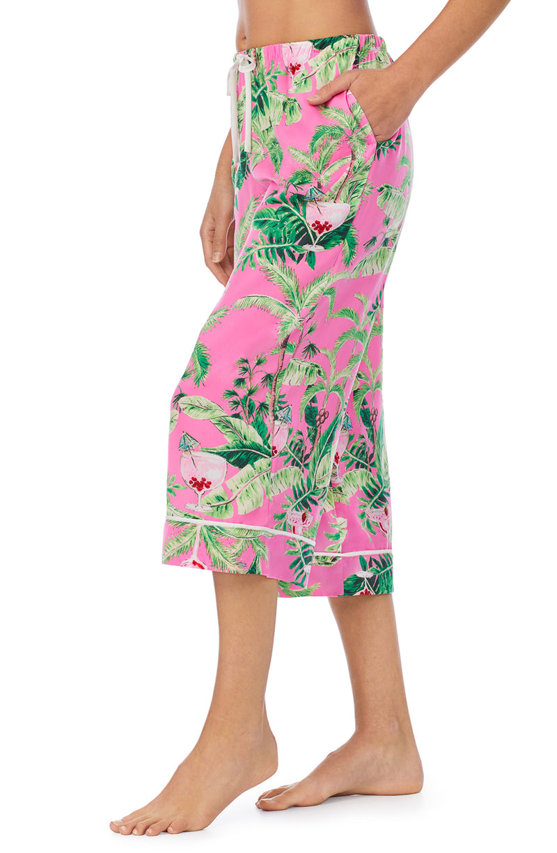 A lady wearing a pink crop pant with green floral pattern.