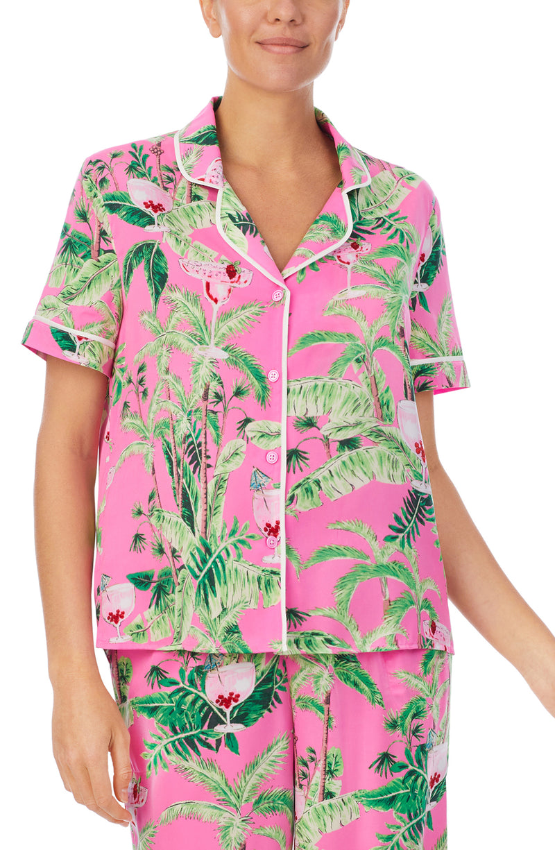 A lady wearing a pink short sleeve top with green floral pattern.
