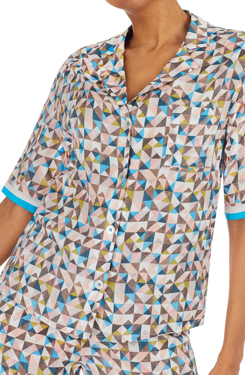 A lady wearing a multi colour short sleeve top with a tile pattern.