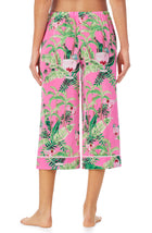 A lady wearing a pink crop pant with green floral pattern.
