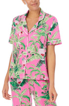 A lady wearing a pink short sleeve top with green floral pattern.