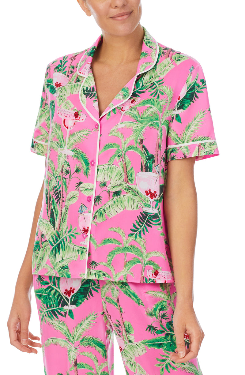 A lady wearing a pink short sleeve top with green floral pattern.