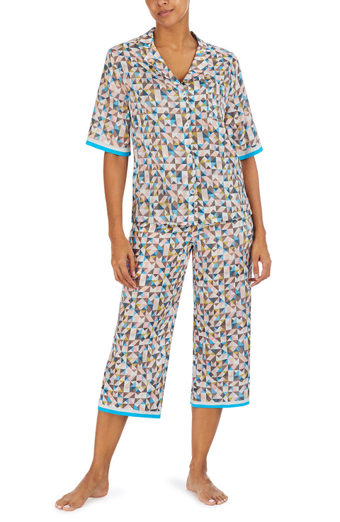 A lady wearing a multi colour short sleeve top with a tile pattern.