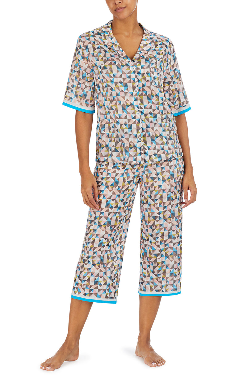 A lady wearing a multi colour short sleeve top with a tile pattern.