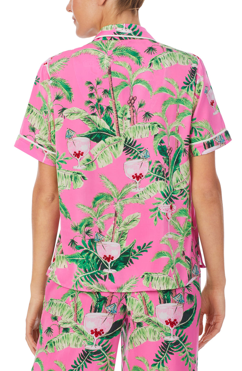 A lady wearing a pink short sleeve top with green floral pattern.