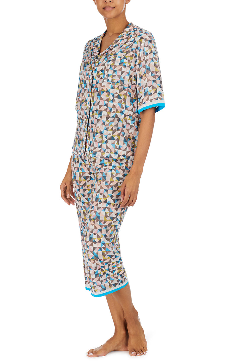A lady wearing a multi colour short sleeve top with a tile pattern.