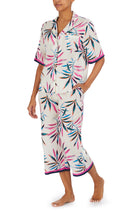 A lady wearing a white short sleeve top with multi colour palm leaves pattern