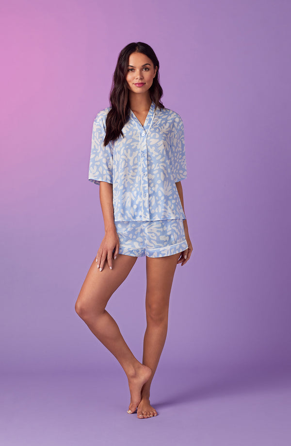 A lady wearing blue short sleeve abbey pj set with beach please coral print.
