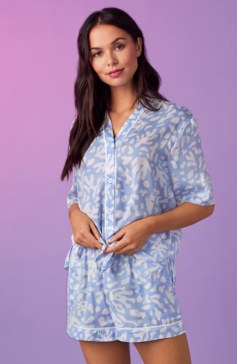 A lady wearing blue short sleeve abbey pj set with beach please coral print.