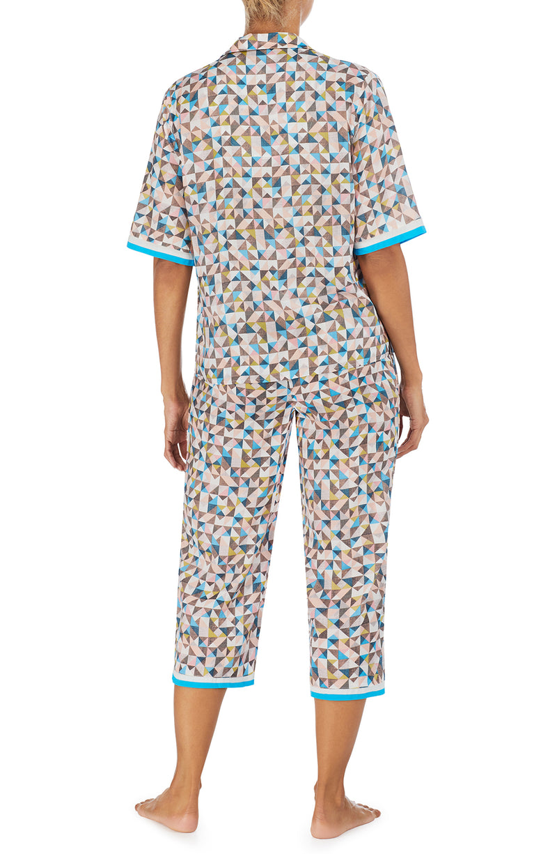 A lady wearing a multi colour short sleeve top with a tile pattern.