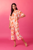 A lady wearing orange short sleeve tilden pj set with star struck print.