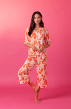 A lady wearing orange short sleeve tilden pj set with star struck print.