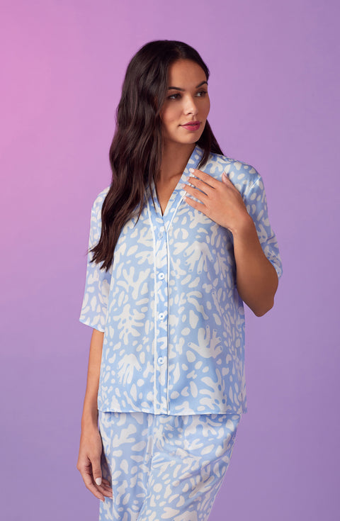 A lady wearing blue short sleeve tiden pj set with beach please coral print. 