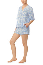 A lady wearing blue short sleeve abbey pj set with beach please coral print.