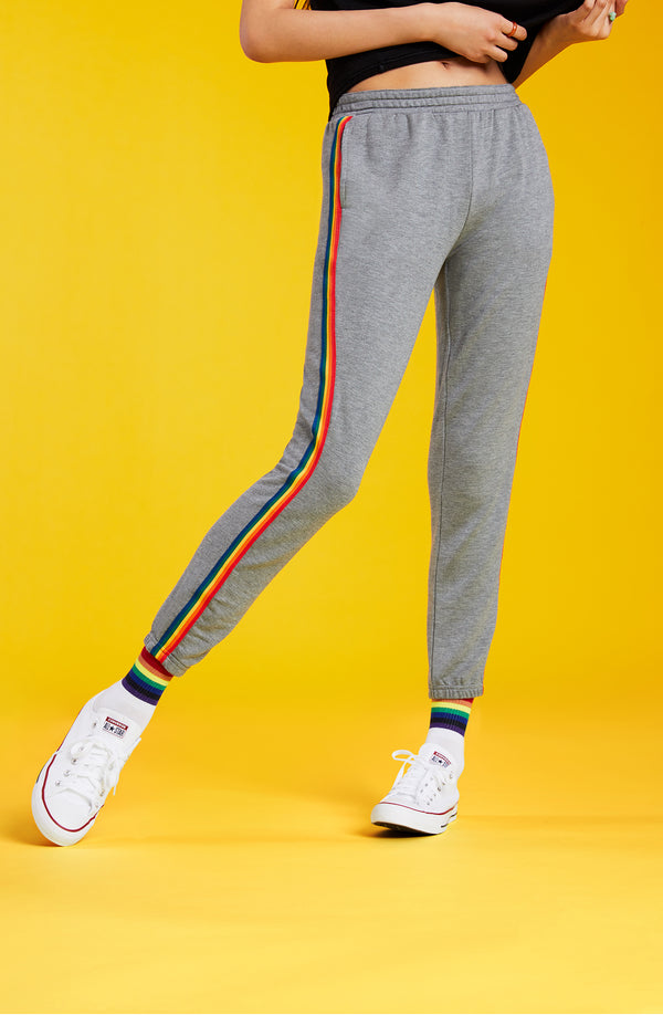 A lady wearing a grey unisex jogger with pride stripes in side.