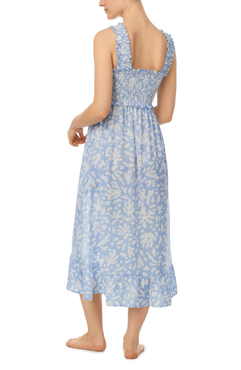 A lady wearing blue willow chemise with beach please coral print.