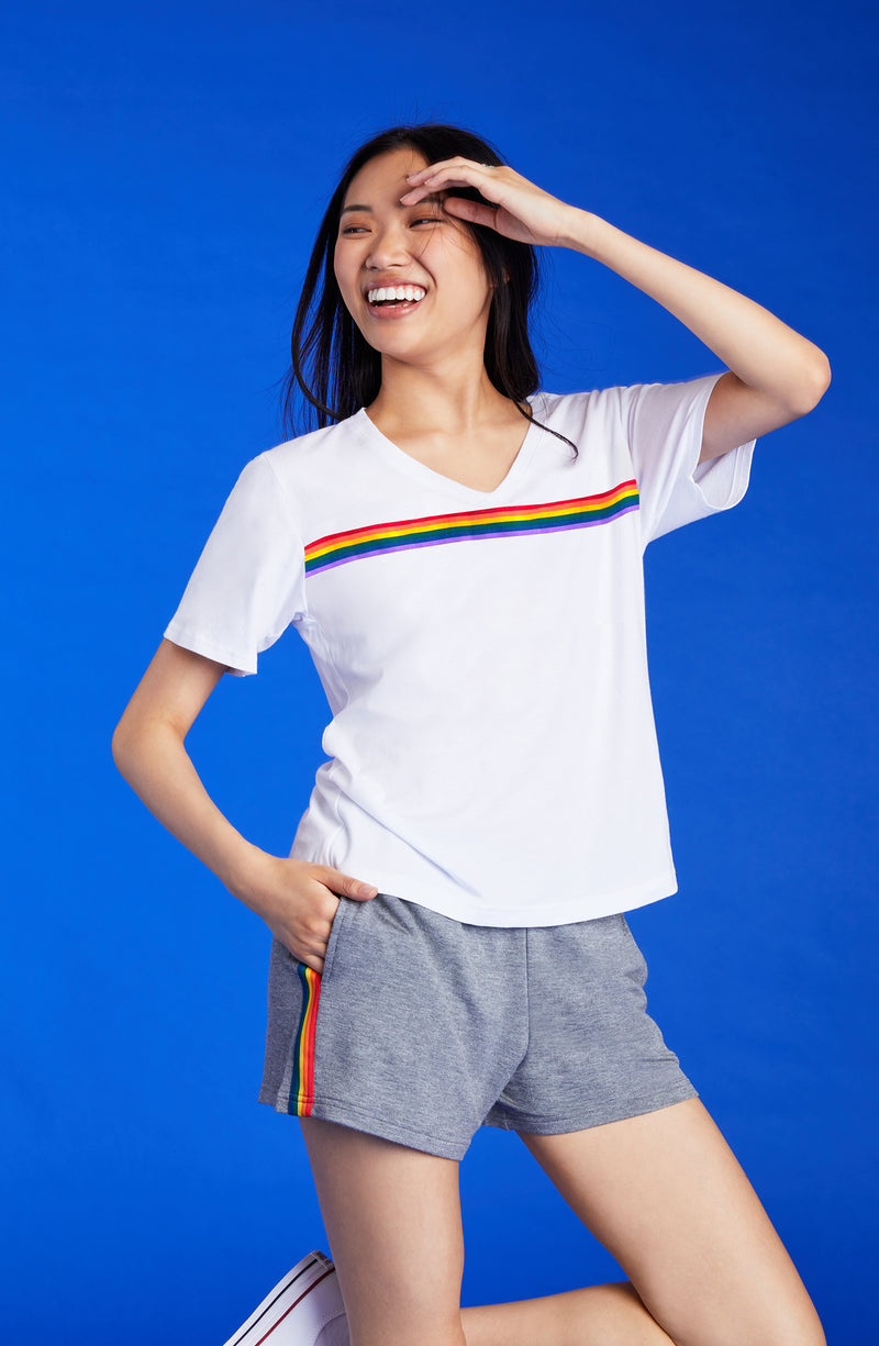 A lady wearing a white unisex T-Shirt with pride stripes.